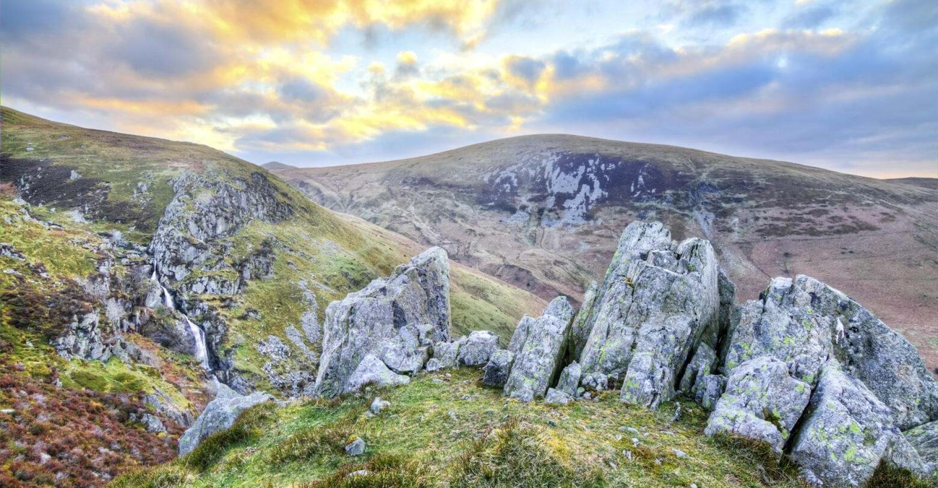 The setting sun casts brilliant golden colors on the rolling landscape near Aber Falls, Wales, UK.