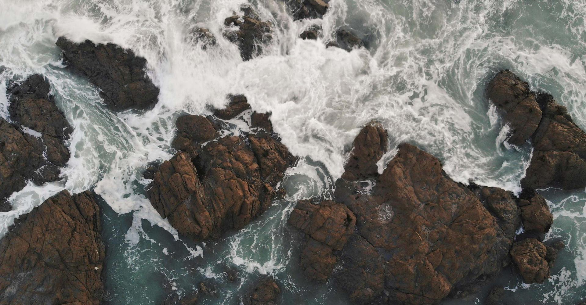 Waves crash onto the rocks that line the cliffs along the Cornish Coast in England.